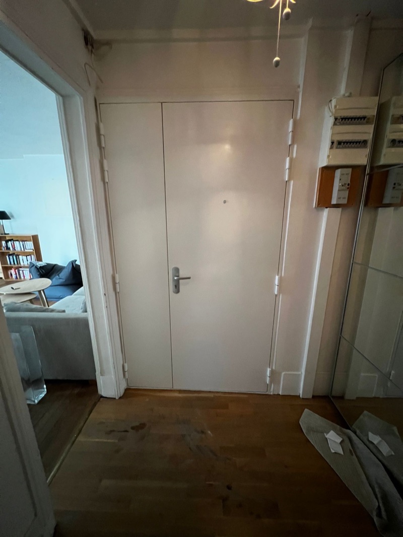 Bloc-porte blindé blanc avec partie fixe latérale, béquille grise et judas optique, posé dans l'entrée d'un appartement — Charenton-le-Pont