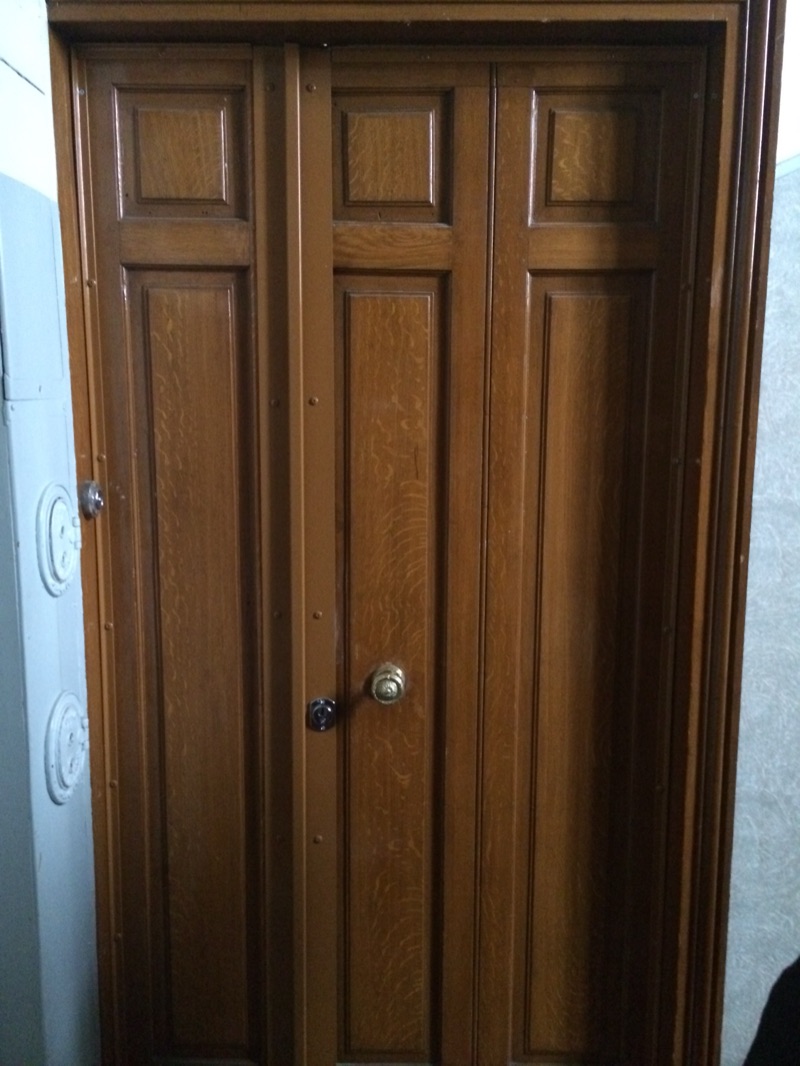 Porte d'entrée en chêne à trois panneaux avec cornière de blindage centrale, bouton de tirage en laiton et cylindre chromé — Charenton-le-Pont
